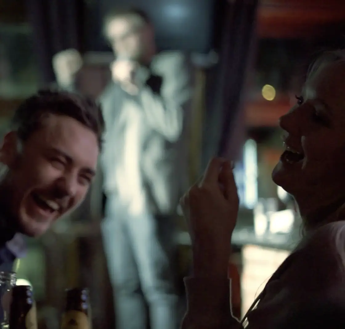 Two people laughing in the audience at a comedy club